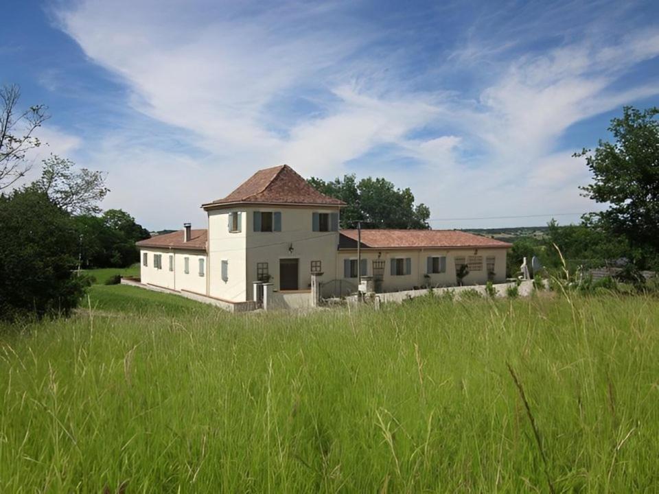 a large white house in a field of grass at Le Manoir Monlezun in Monlezun