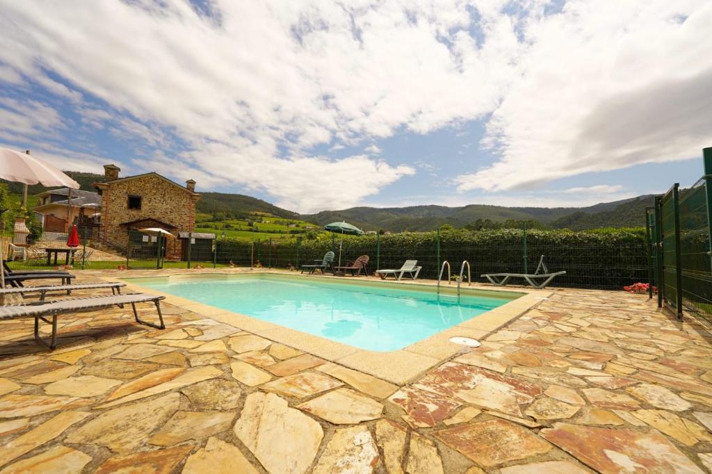 a swimming pool with a stone patio and a fence at El Cuelebre in Arancedo
