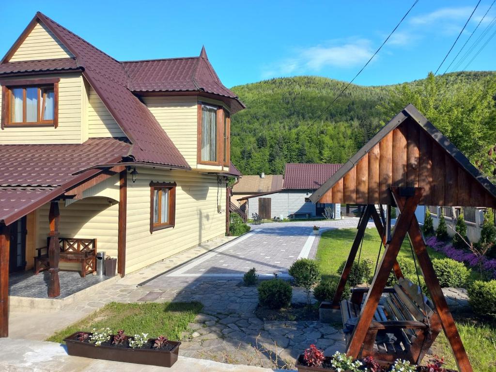 a house with a gambrel roof and a patio at Yaremche Potik Guest House in Yaremche