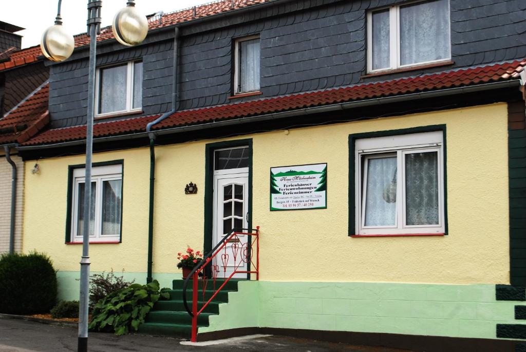 a yellow house with a sign on the door at Guest house Mückenheim in Benneckenstein