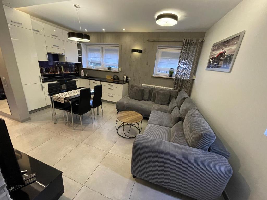 a living room with a couch and a table and a kitchen at Apartament Ala in Zabrze