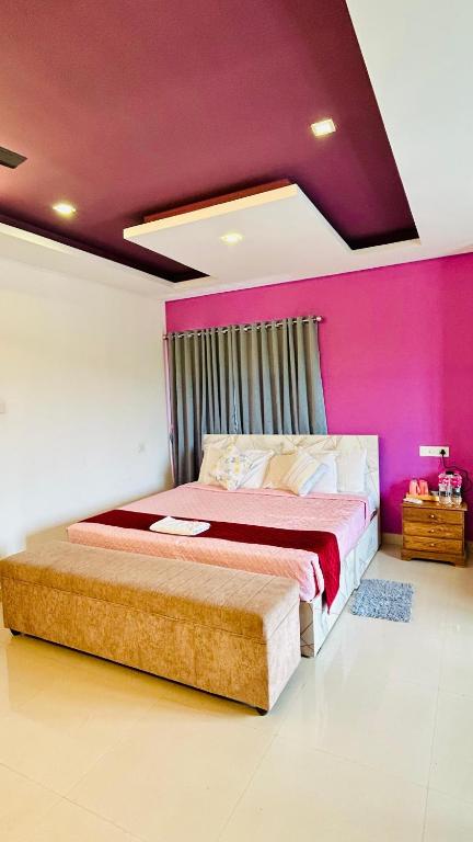 a bedroom with a large bed with a pink wall at Palmyra Hotel and Suites in Kollam