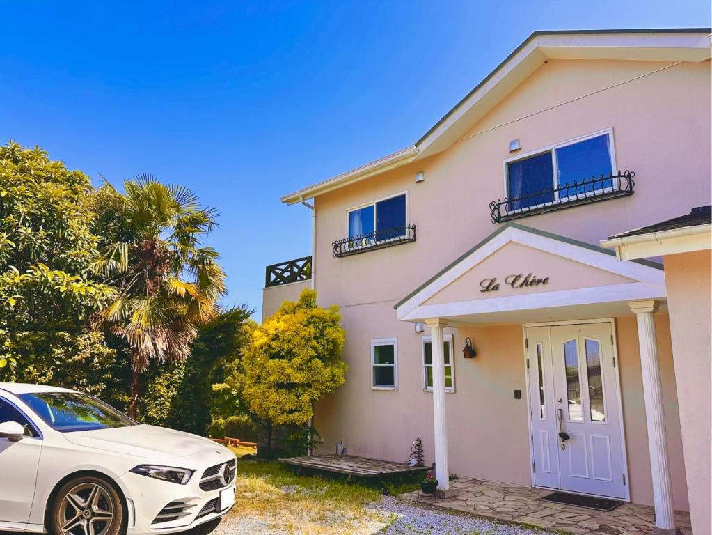 a white car parked in front of a pink house at ラシェール 伊豆 ガーデンテラス AWA Resort in Ito