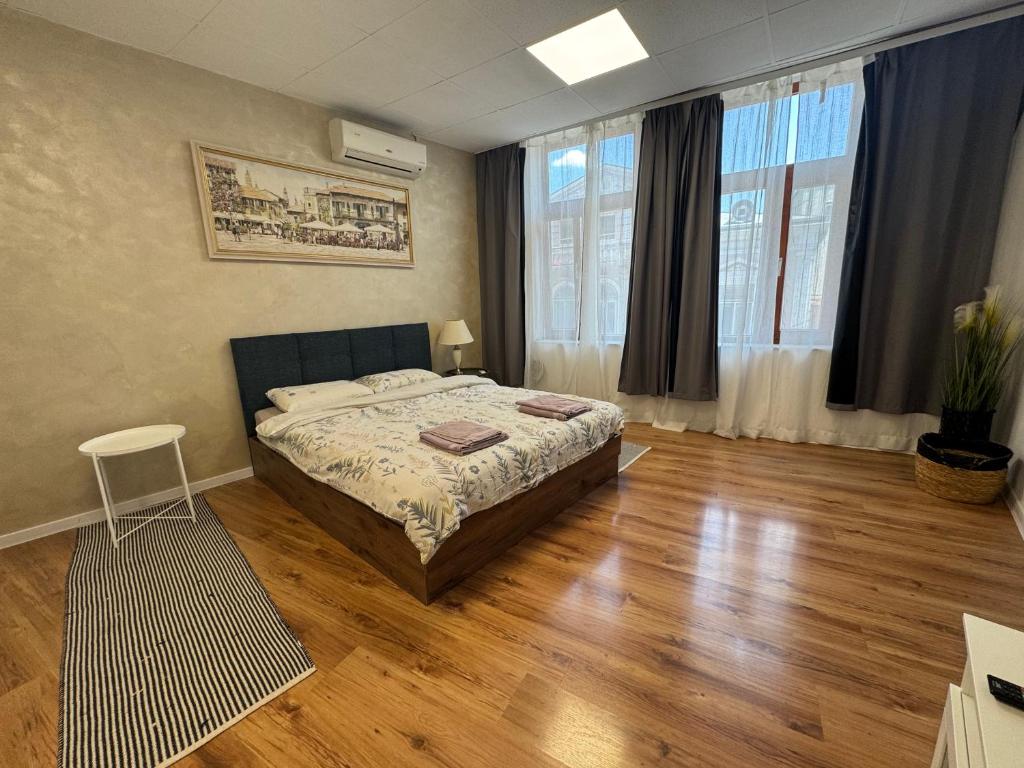 a bedroom with a bed and wooden floors and windows at habitat Heart of Ruse Apartment in Ruse