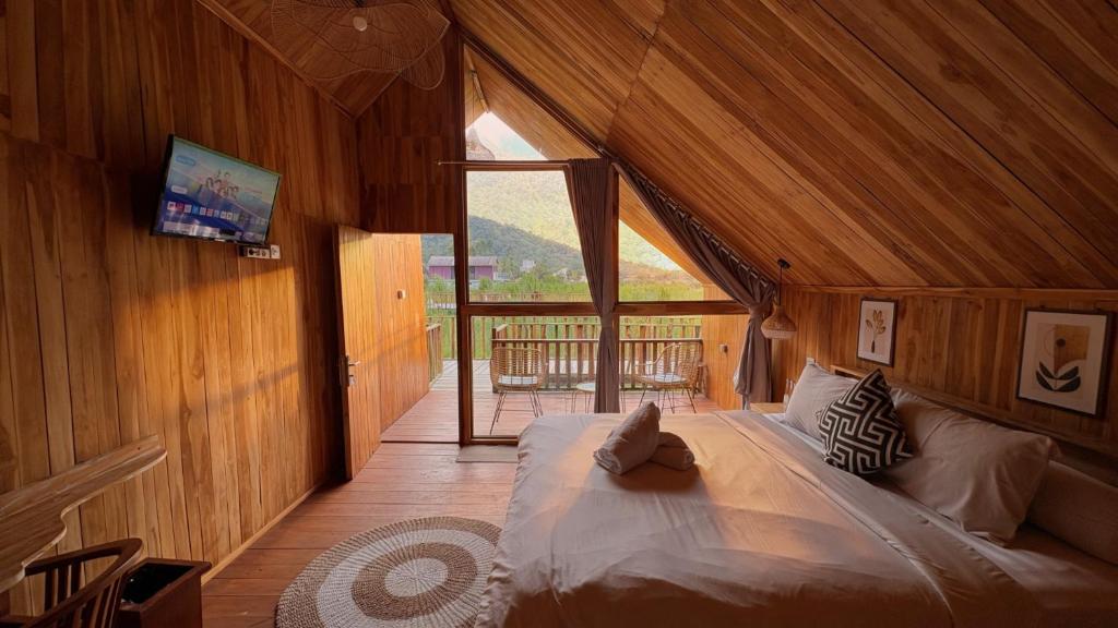 a bedroom with a large bed in a wooden room at Dynasty Glamping Bedugul in Bedugul