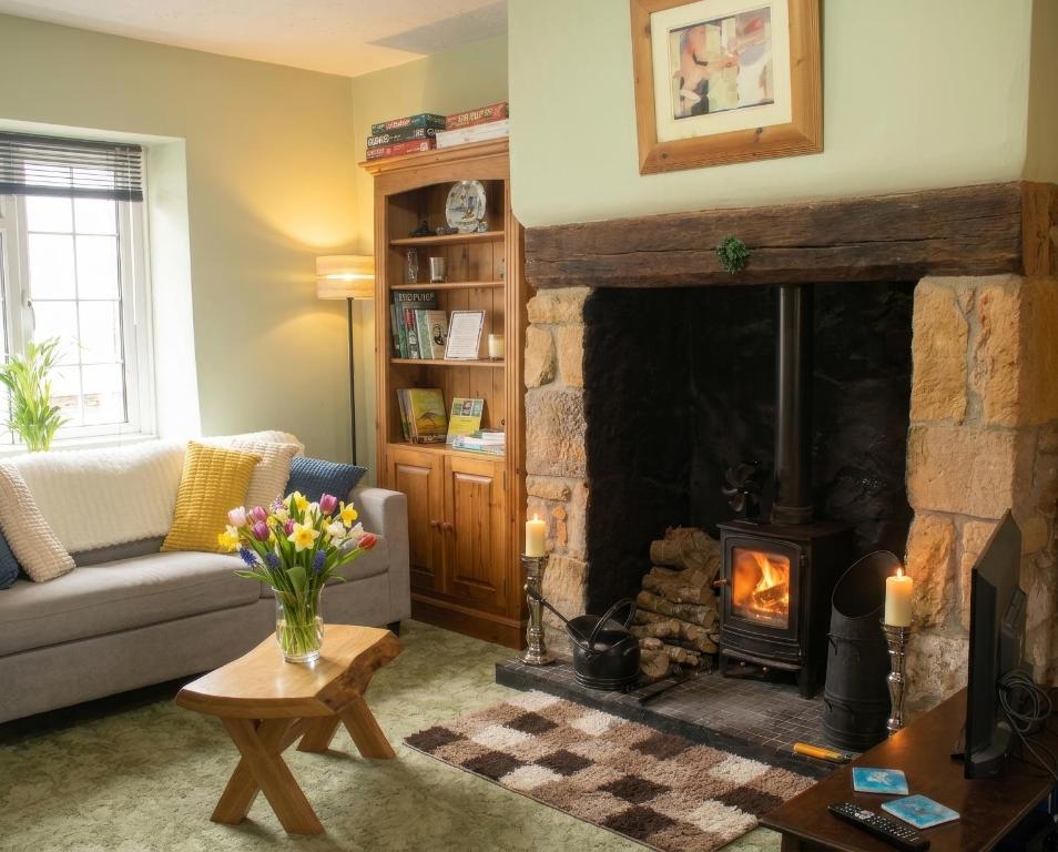 a living room with a fireplace and a couch at Motcombe Cottage in Hatherleigh