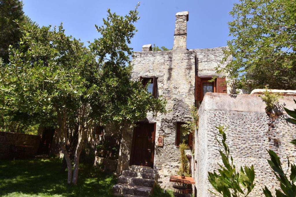 an old stone house with a tree in front of it at Villa Fümehan Tarihi Rum Taş Ev Since 1820 in Kayakoy