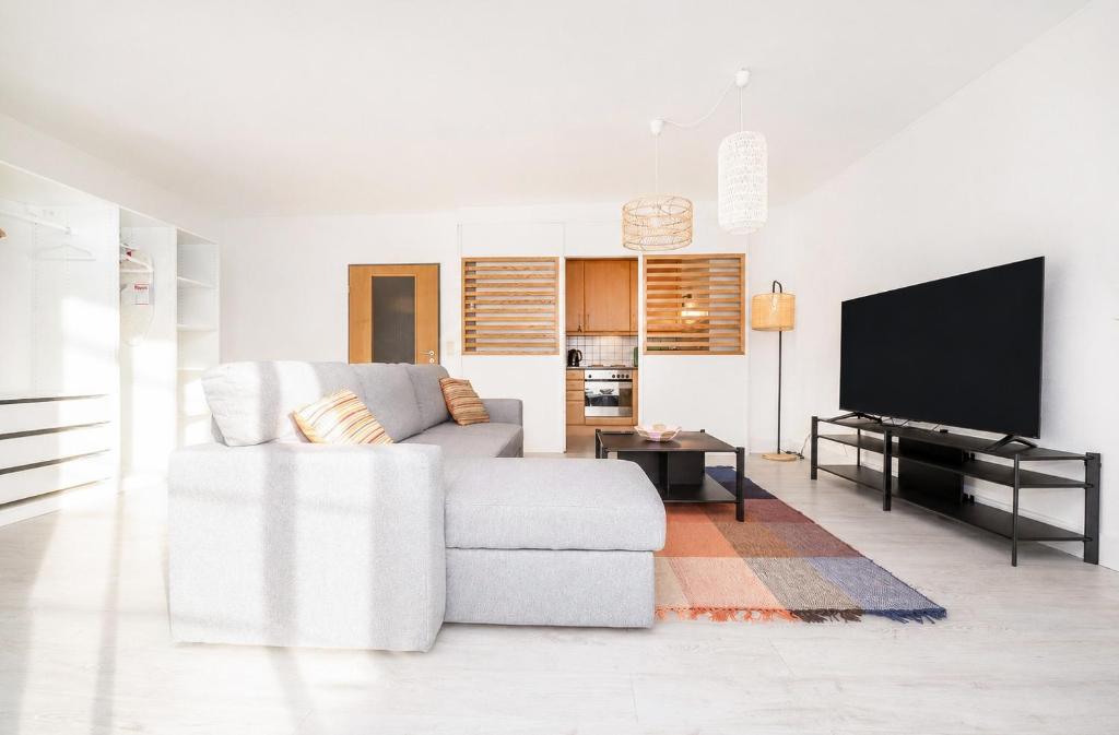 a white living room with a couch and a flat screen tv at Grand Rue Studio - sleeps 5 in Luxembourg