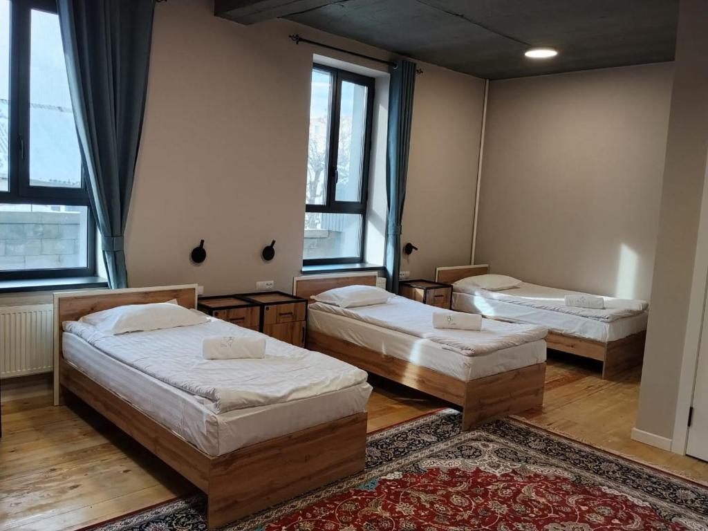 a room with three beds and a rug at Hostel 78 in Karakol
