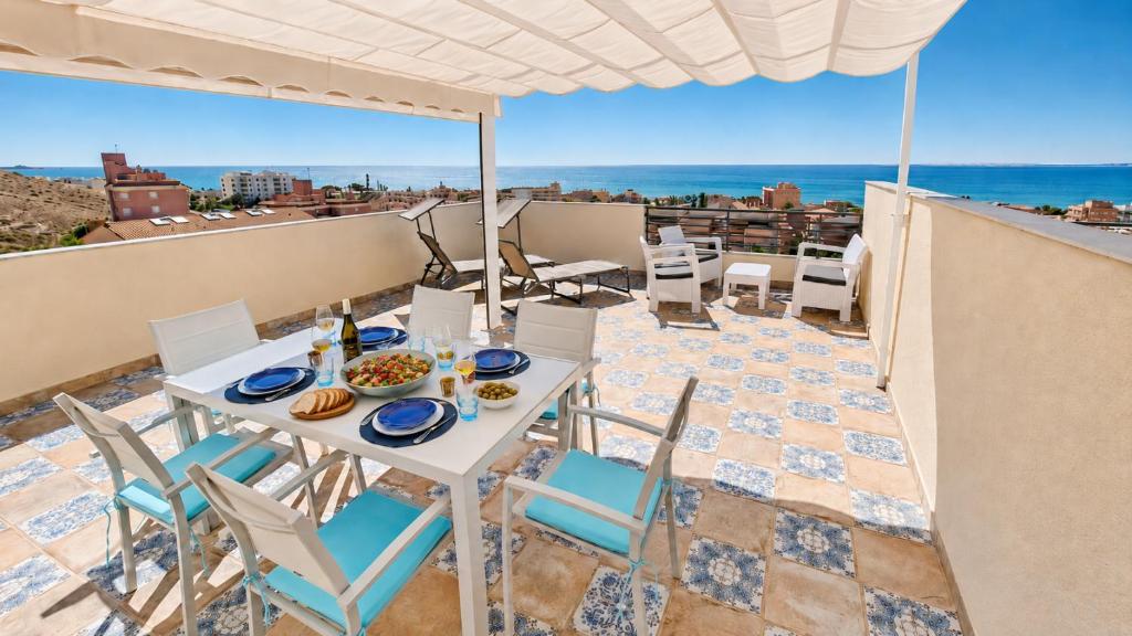a table and chairs on a balcony with a view of the ocean at Penthouse with Panoramic View Santa Pola in Santa Pola