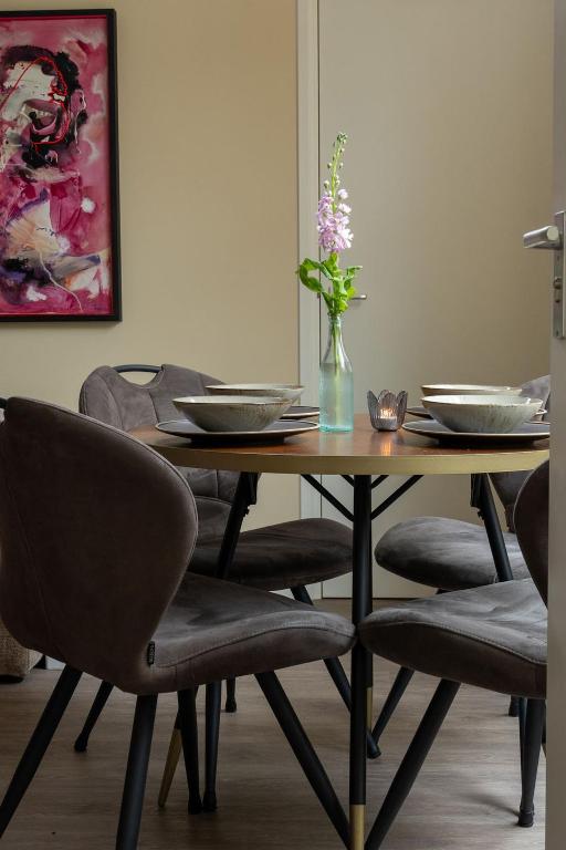 a dining room table with chairs and a vase with flowers at Het Bakkershuus in Gramsbergen