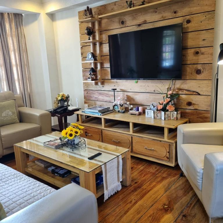 a living room with a large television on a wooden wall at Whyte Pyne Transient House in Baguio