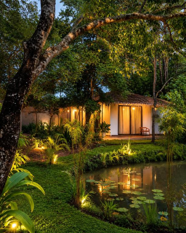 a house with a pond in front of it at Myla Lodge in Anuradhapura
