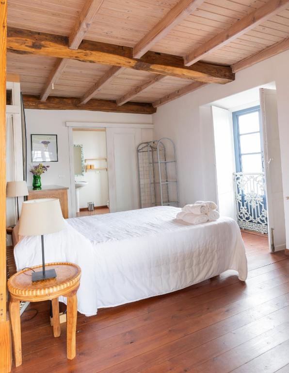 a bedroom with a large white bed and a table at NAMOR-Estudio Galeria in Ribadeo