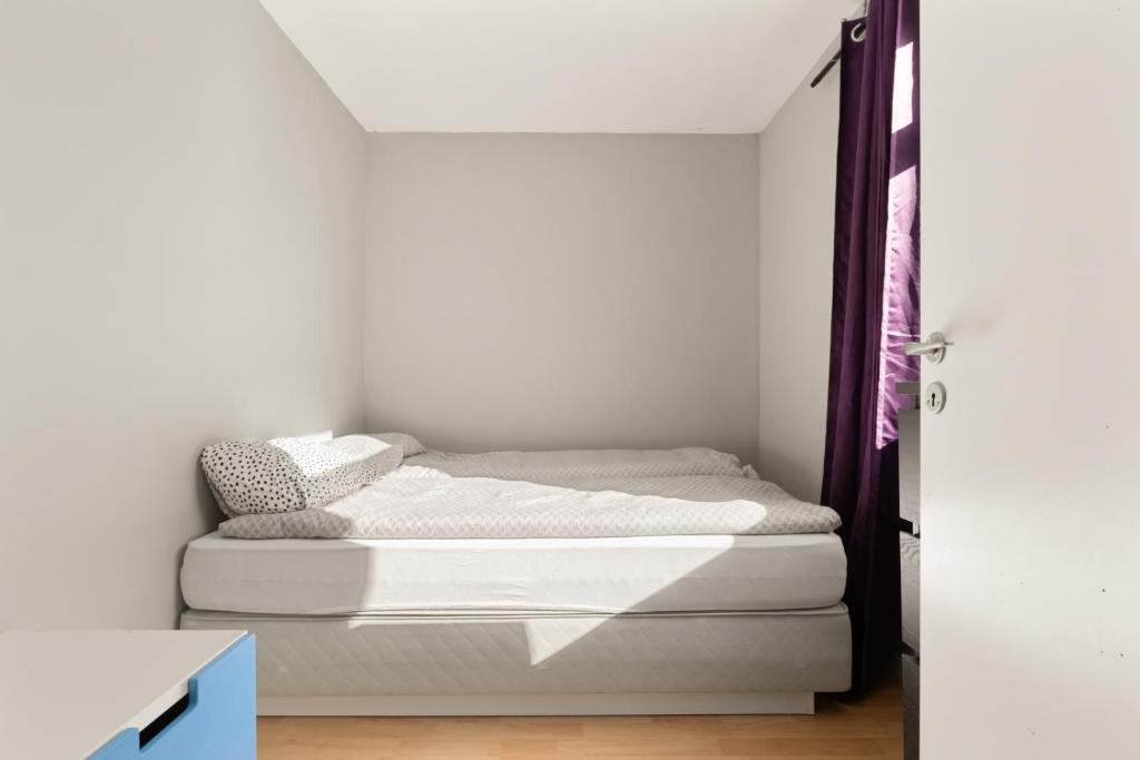 a bed in a room with white walls at Home and Away in Vaksdal