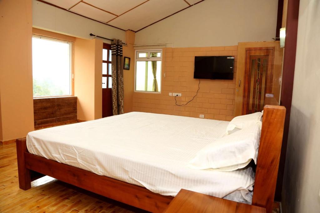 a bedroom with a bed and a tv on a wall at Sunshine retreat in Coonoor