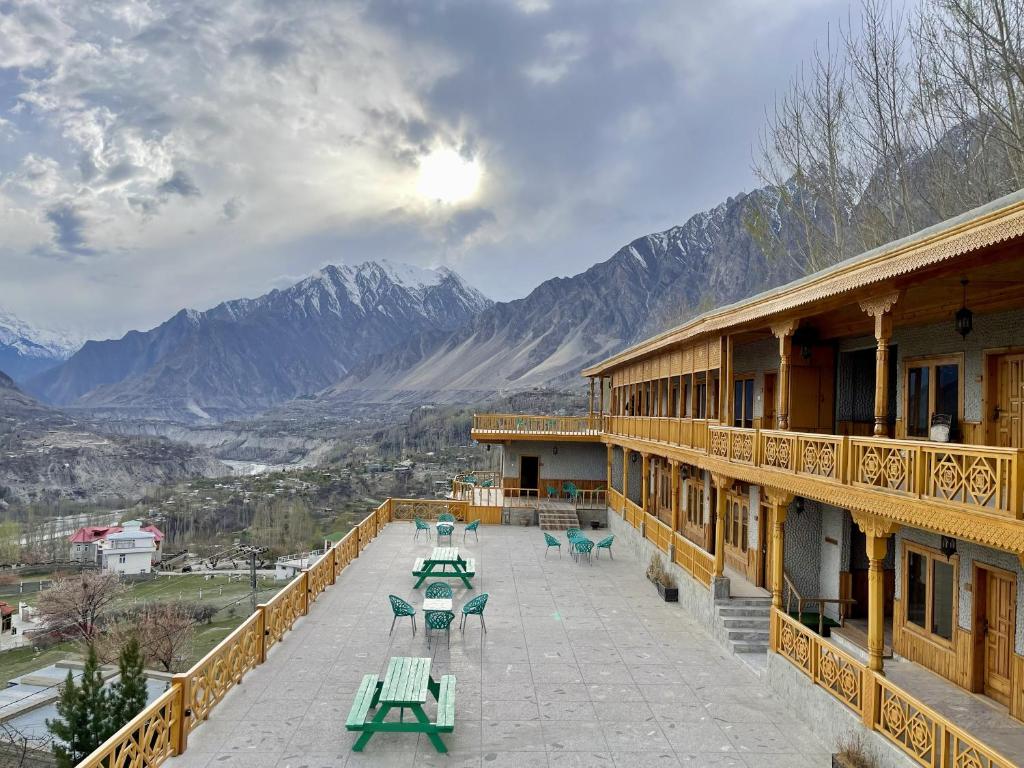 a balcony of a building with picnic tables and mountains at Hunza Embassy Hotel by Zeez in Karimabad Hunza