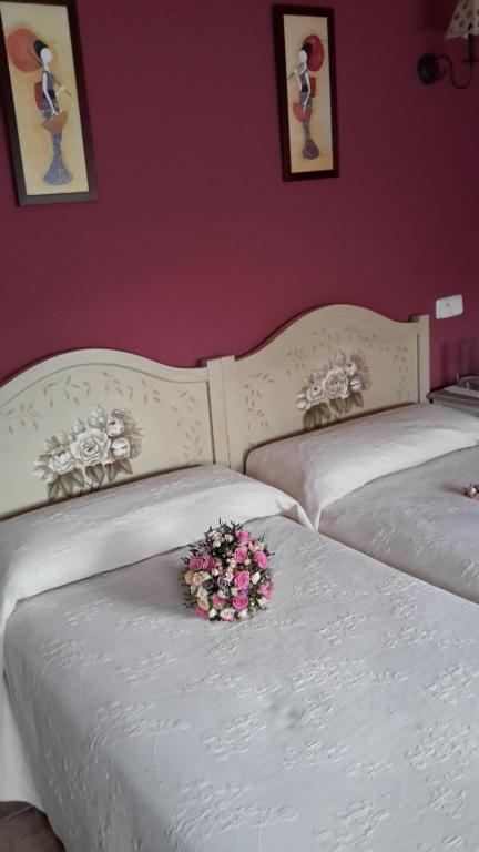 dos camas blancas con un ramo de flores. en Casa de La Paca, en Coca