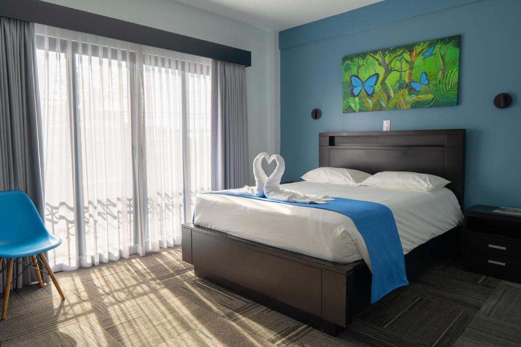 a bedroom with a large bed with blue walls at Hotel Luckys in San Isidro de El General