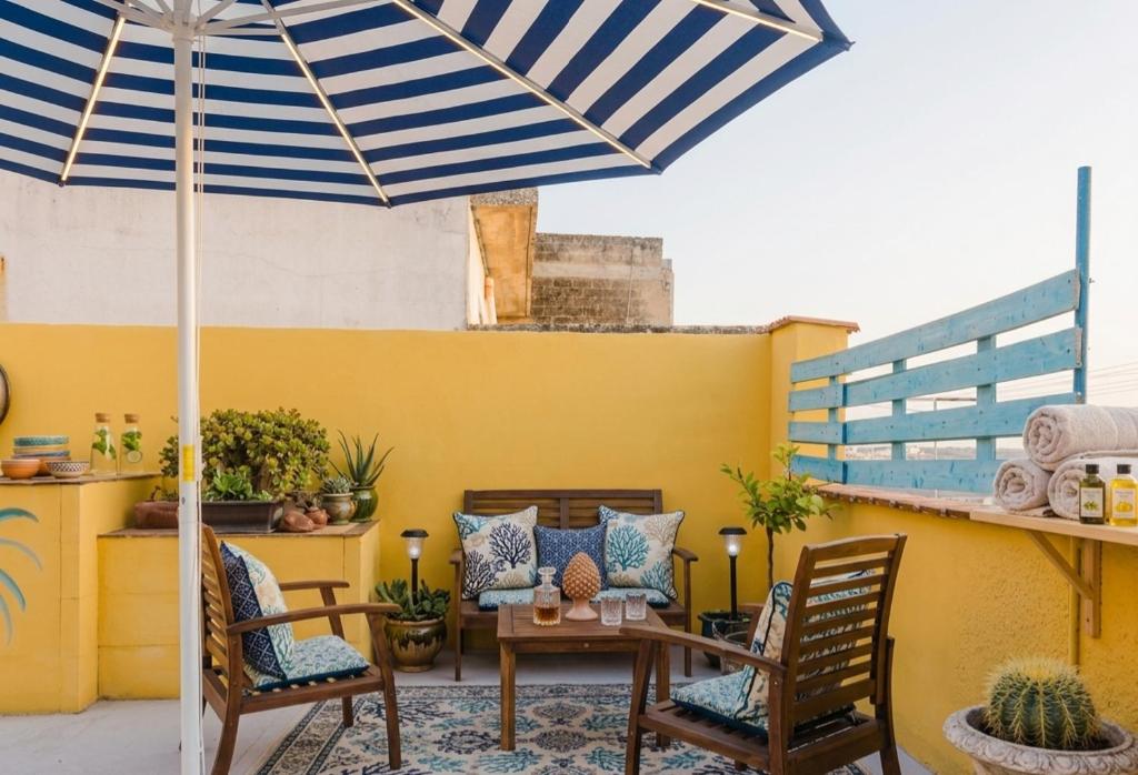 a patio with a table and chairs and an umbrella at Casa d'Artista con Terrazza Panoramica nel Borgo" Ajman house in Sambuca di Sicilia