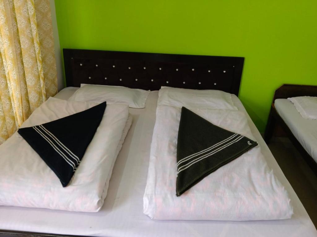 a bed with black and white pillows and a green wall at Vinod Tourist Lodge in Gupta Kāshi