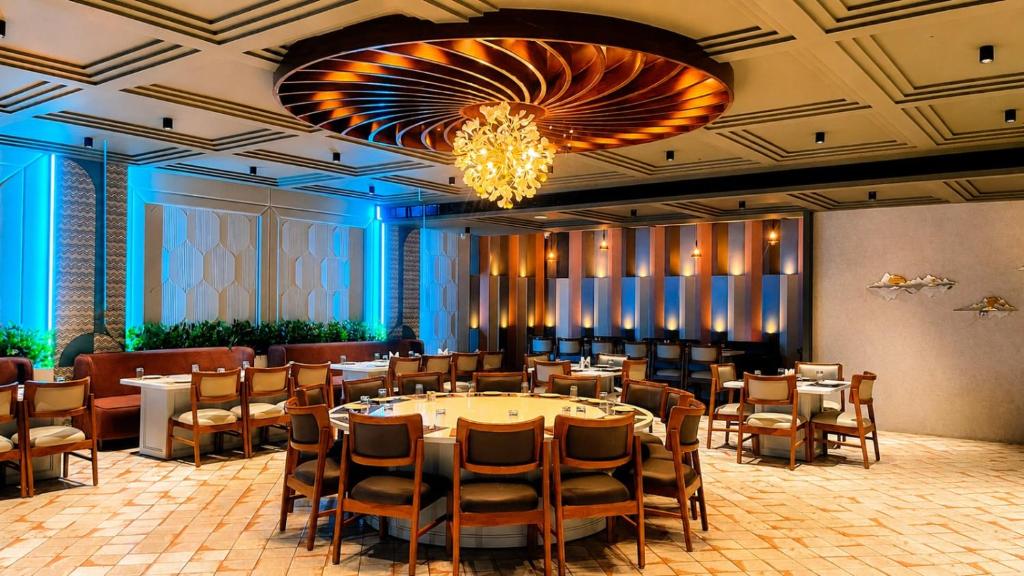 a dining room with tables and chairs and a chandelier at Veerasa Hotel in Hanumāngarh