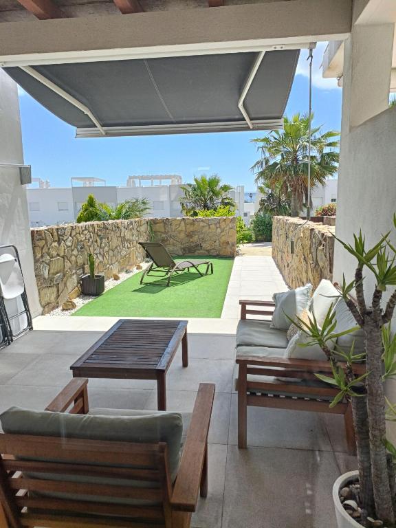 an outdoor patio with a table and chairs and a lawn at Casa adosada Rompeolas-Atlanterra in Zahara de los Atunes