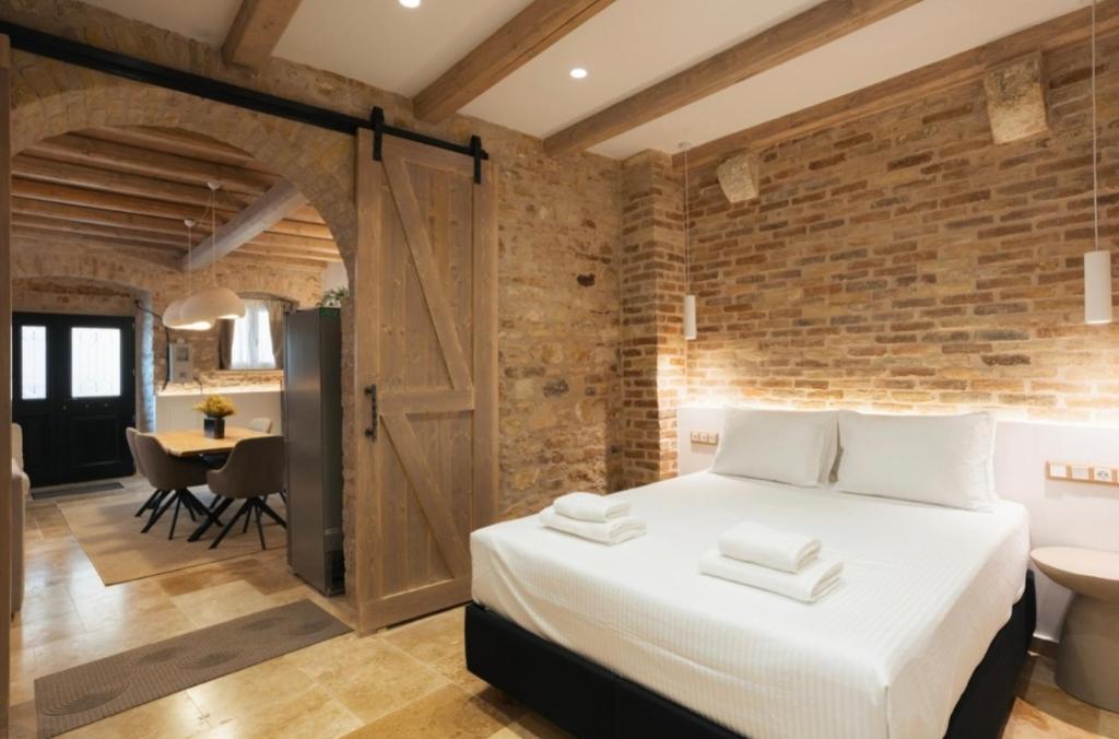 a bedroom with a large bed and a brick wall at Arco Segreto Apartment, Old Town in Corfu