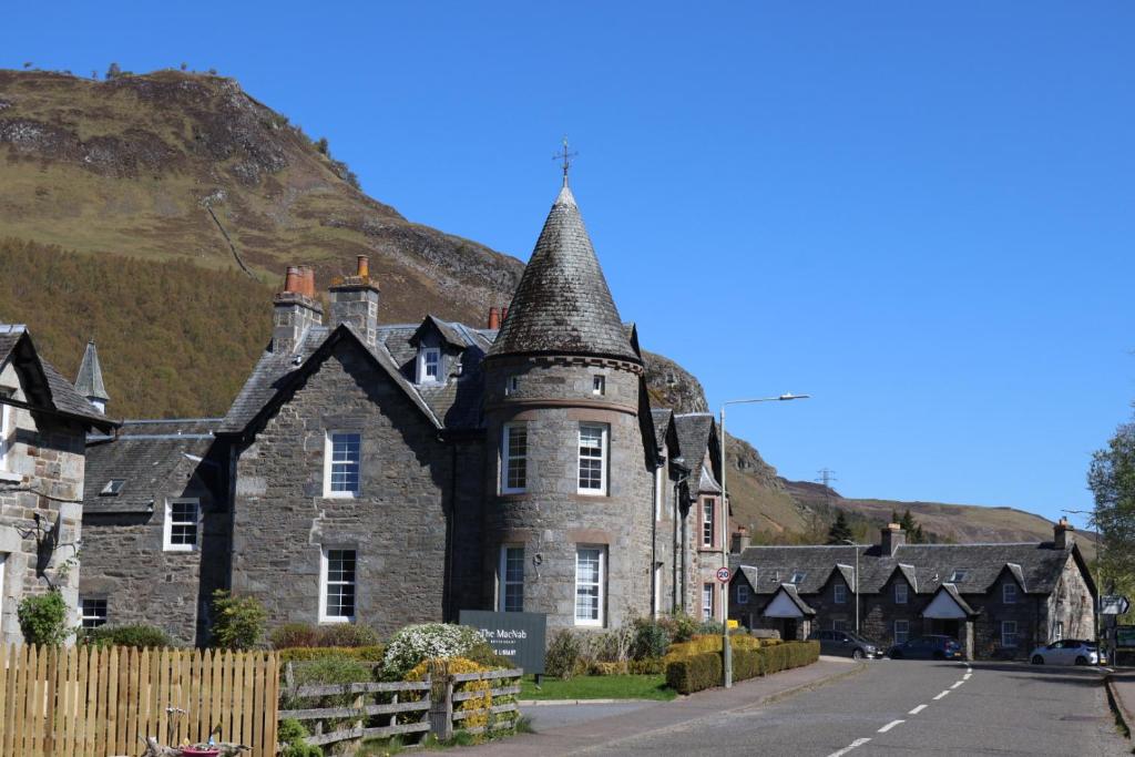 an old stone building with a mountain in the background at Dunalastair Hotel Suites in Kinloch Rannoch