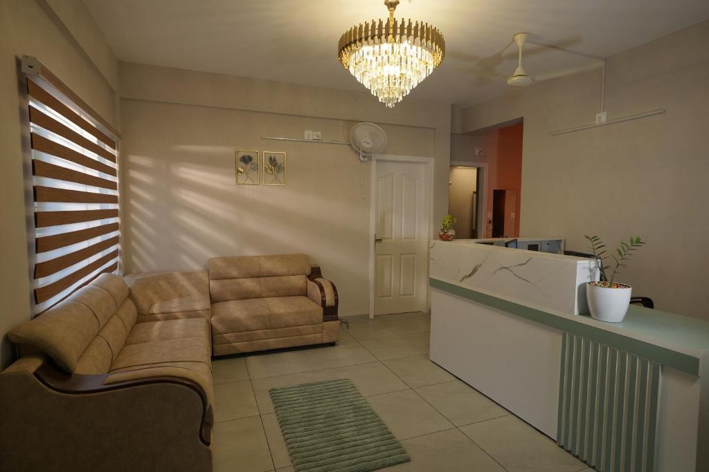 a living room with a couch and a kitchen with a chandelier at Blue Pearl Residency in Trivandrum