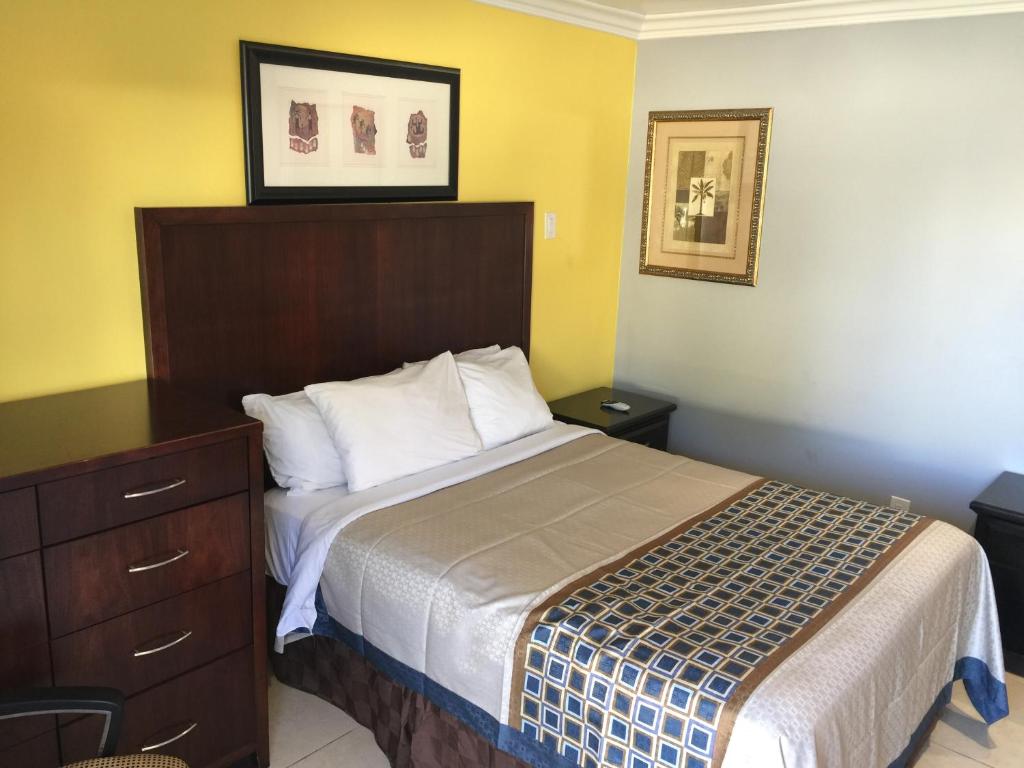 een slaapkamer met een bed met een houten hoofdeinde en een dressoir bij Crenshaw Inn Motel in Los Angeles
