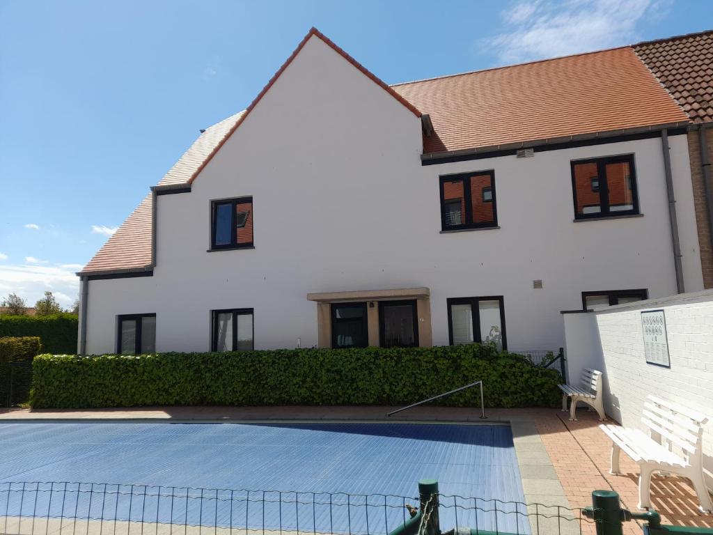 a house with a swimming pool in front of it at Duplex met zwembad Neoportus in Nieuwpoort