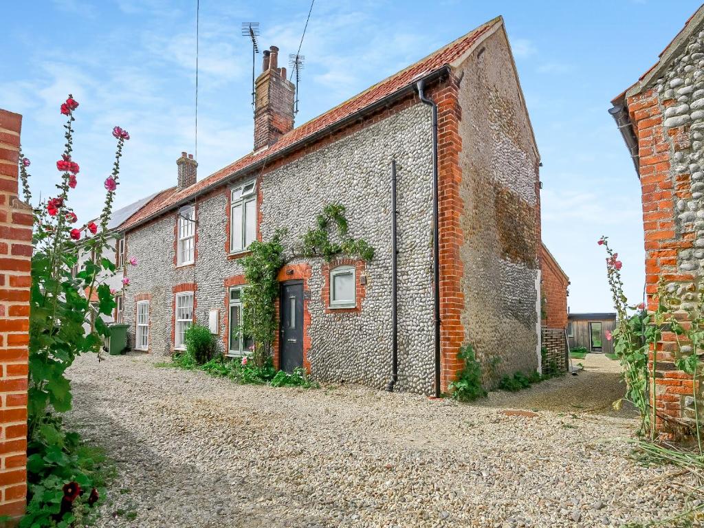 an old brick house on a gravel road at Greenrush Cottage in Blakeney