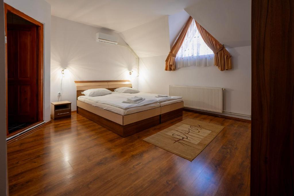 a bedroom with a bed and wooden floors and a window at Casa Toma in Sovata