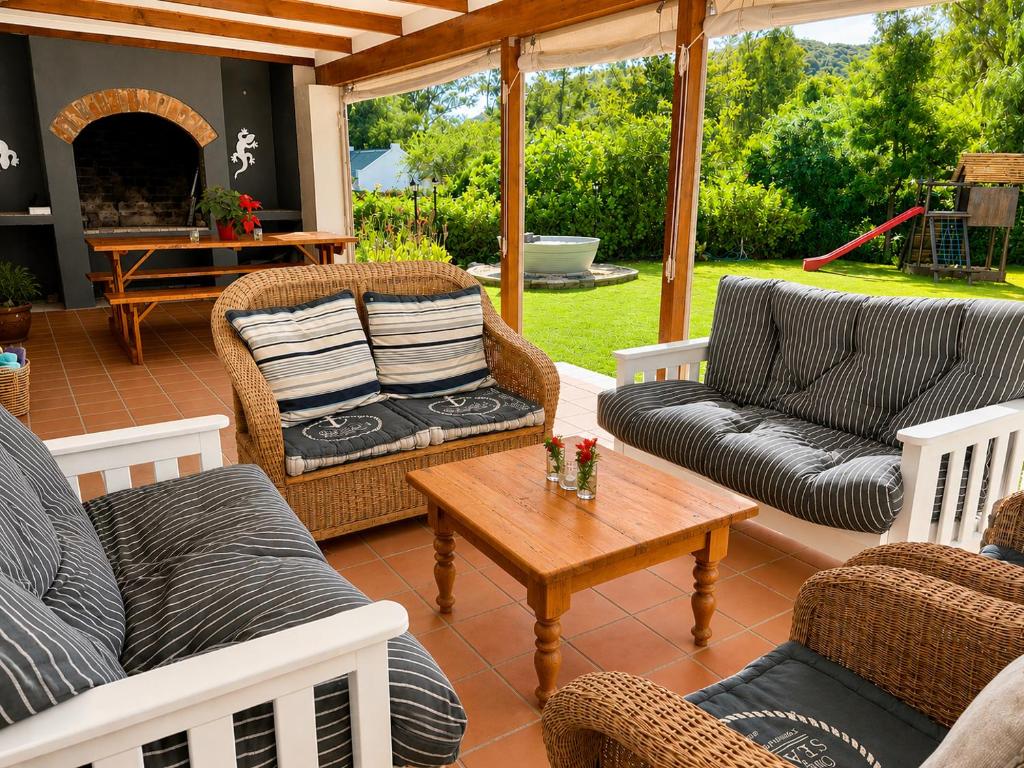 a screened in porch with couches and a coffee table at Adrenalin Addo Manor House in Addo