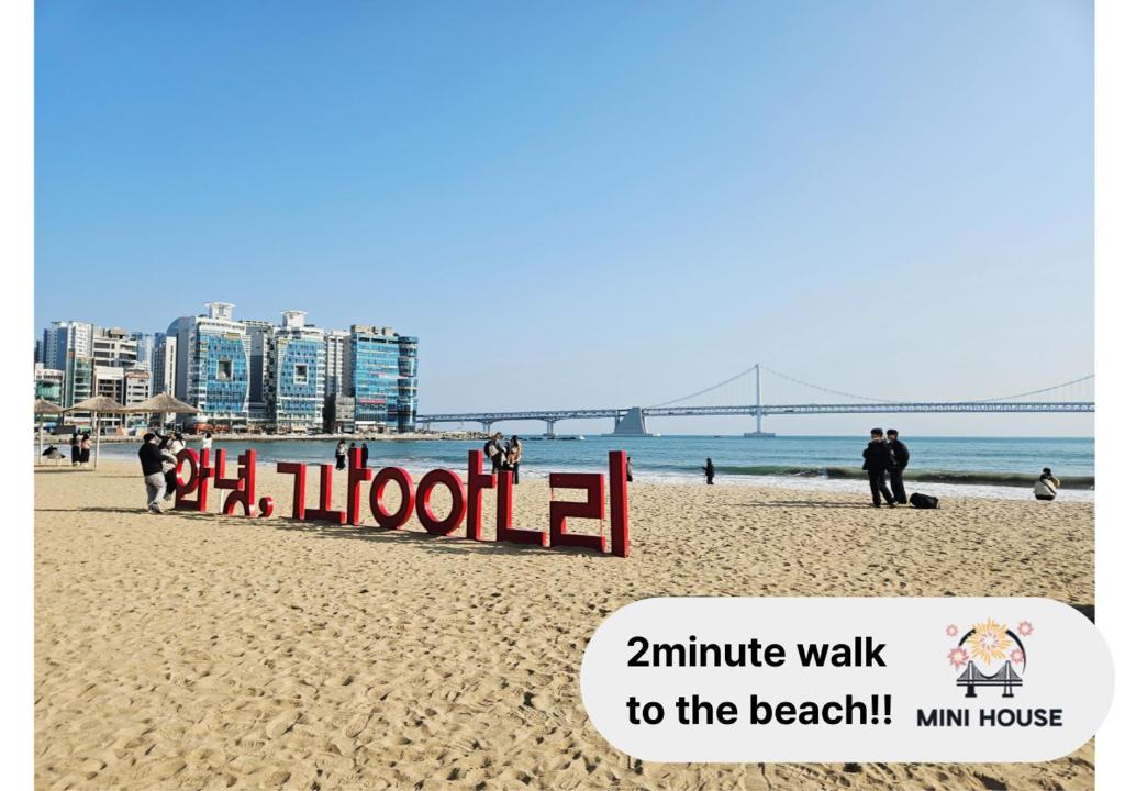 a sign on a beach with a bridge in the background at Mini House in Busan