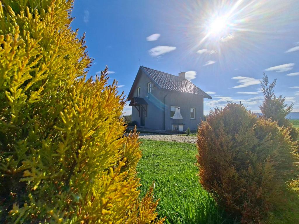 a house in a field with the sun in the sky at Idzikowianka in Idzików