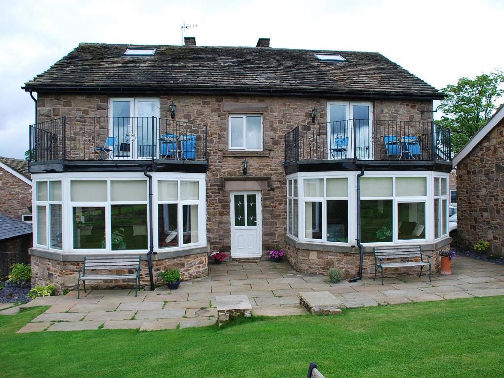 a brick house with a patio with benches in the yard at Shallcross Hall Cottages - Combs in Taxal