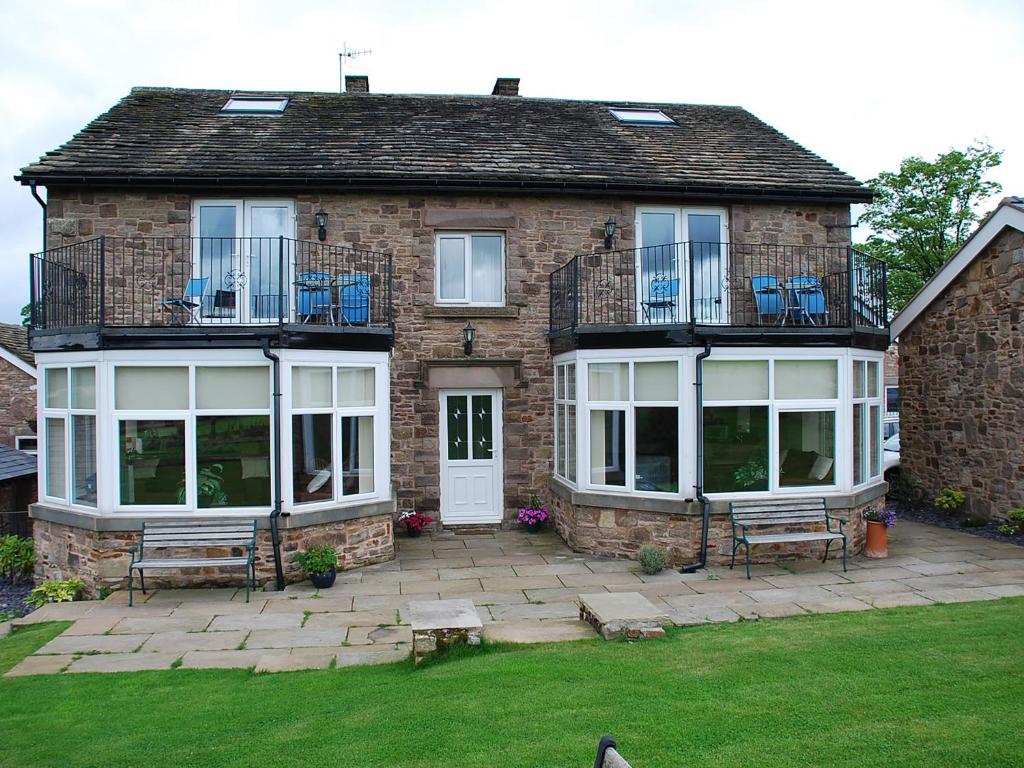 a brick house with a patio with benches in the yard at Shallcross Hall Cottage - Toddbrook - Whaley Bridge in Taxal