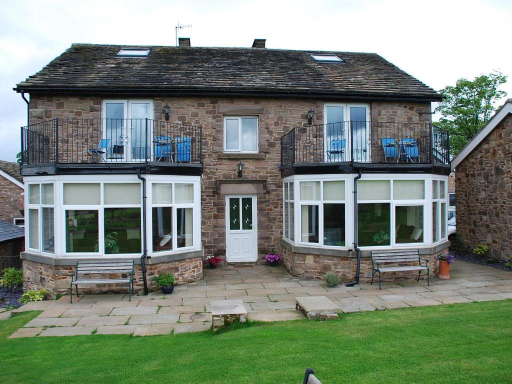 a brick house with two benches in the yard at Shallcross Hall Cottages - Blackbrook in Taxal