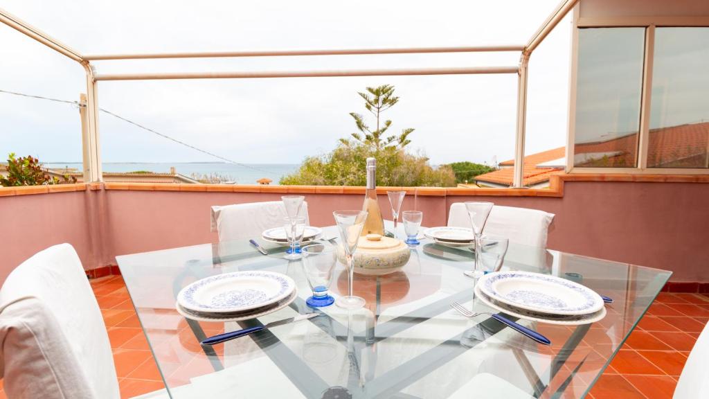 a glass table and chairs on a balcony at Torre del Pozzo Seaview Retreat Sunset Terrace in S'archittu Cuglieri