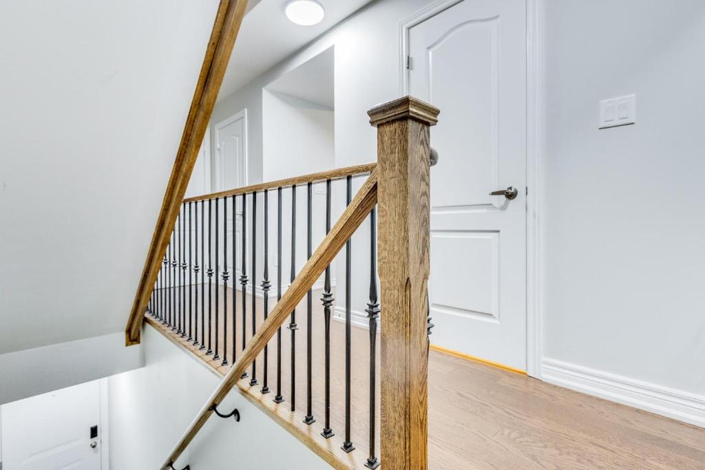 a staircase with a wooden rail and a white door at spacious 3 bedroom space in Markham