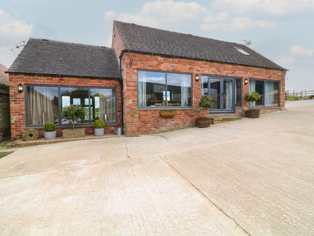 a brick house with windows and potted plants at The Croft, Home Farm in Ripley