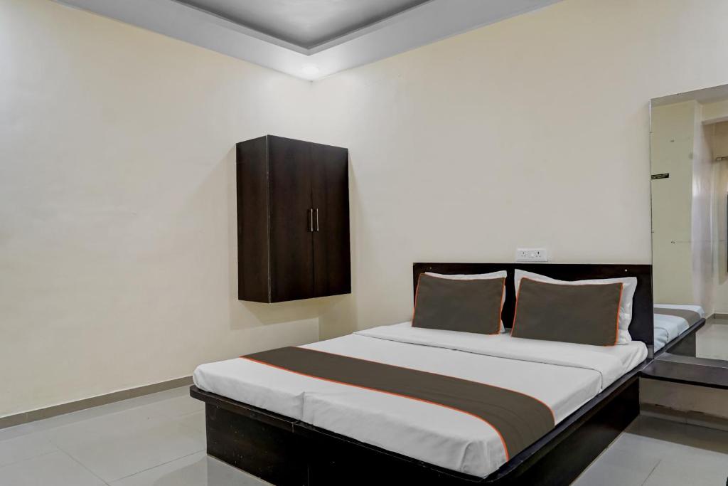 a bedroom with a bed with a cabinet on the wall at Hotel O Parinda Lodging in Chinchwad