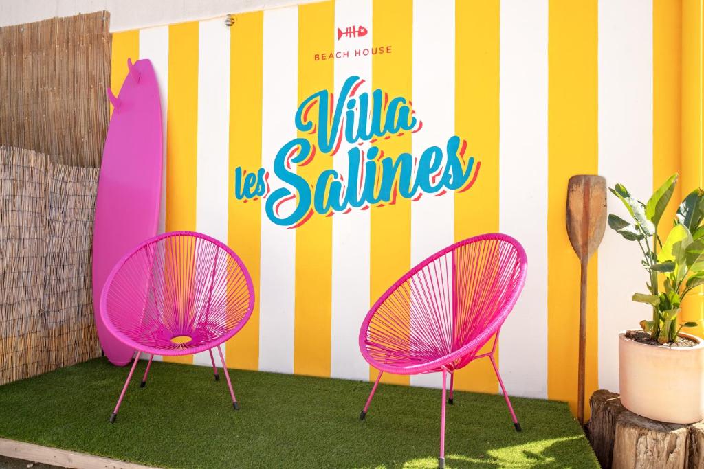 two pink chairs and a surfboard against a wall at VILLA LES SALINES Maison de Vacances au Grau du Roi in Le Grau-du-Roi