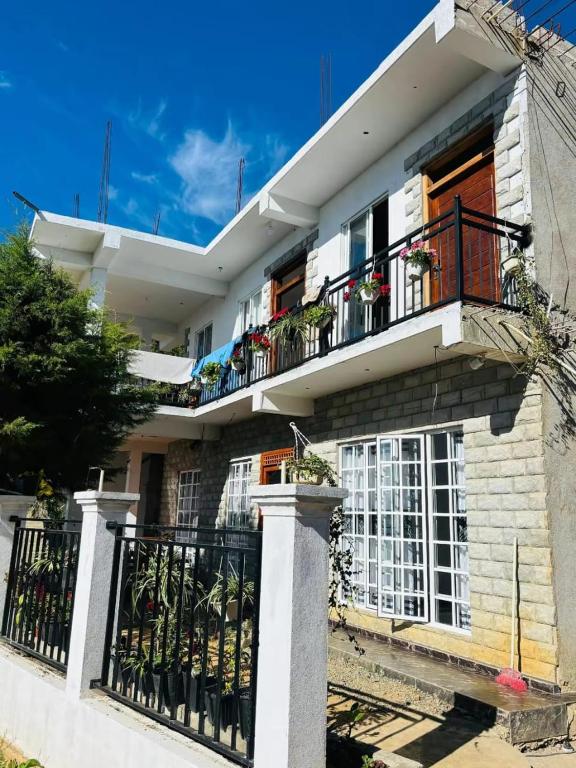 a white house with a balcony with potted plants at Taniya Sunview - Villa in Nuwara Eliya