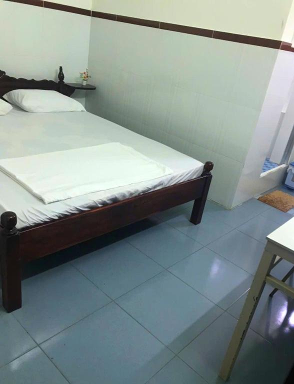 a bed sitting in a room with a white floor at Khách sạn Thảo Minh in Lagi