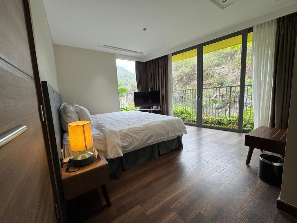 a bedroom with a bed and a balcony with a television at Sky villa on the beach in Cat Ba
