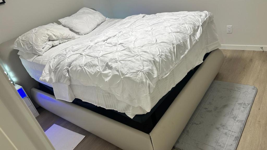 a bed with white sheets on a blue platform at Comfy-home in YYC