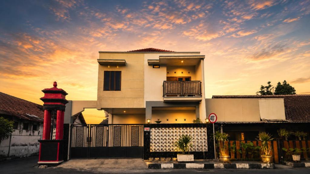a white house with a red pole in front of it at Griya Mentari Homestay in Yogyakarta